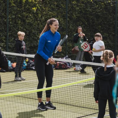 Woman teaching tennis to children